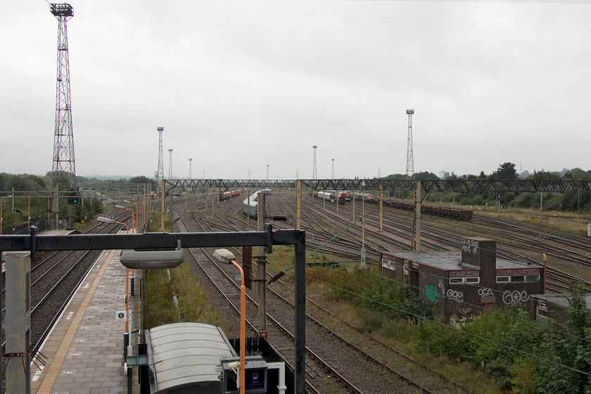 Bescot Yard from station footbridge 
 With the rain beginning to fall I turned the camera south from Bescot Stadium's station footbridge towards the yard. It is clear that this northern end of the yard does not see much use now with just some stored wagons in view. Further south there are huge amounts of stone and ballast where Network Rail operate their infrastructure work that spans out all over the network. The derelict land and rails to the far right of this photograph are where West Midlands Trains want to build their new electric maintenance depot following the rejection of Network Rail's sleeper manufacturing plans at the end of 2019. 
 Keywords: Bescot yard station footbridge