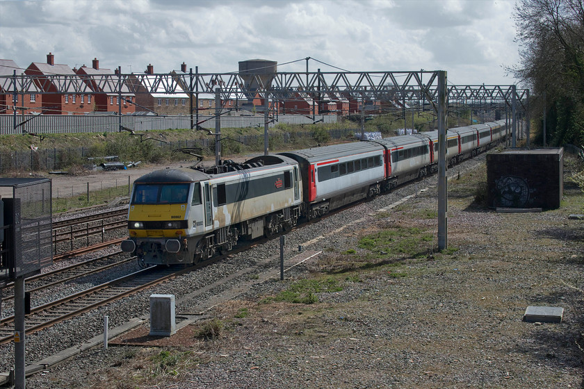 90002, 08.42 Norwich Crown Point-Crewe HS (5Z90, 45E), site of Roade station 
 Running over half an hour early, 90002 'Eastern Daily Press 1870-2010 Serving Norfolk for 140 Years' leads a mixed bag of former Greater Anglia Mk. III stock and a couple of DVTs past the site of Roade station. The de-branded locomotive and stock were running as the 5Z90 08.42 Norwich Crown Point to Crewe's holding sidings operated by Locomotive Services Limited (LSL) on behalf of Greater Anglia. It is surprising that the Class 90 is still wearing the nameplates that it received on 31.05.13 from 90004 that previously carried the plates from October 2010. I am not too sure of the future of the stock and of the two DVTs, 82139 and 82143, out of sight on the rear of the train. 
 Keywords: 90002 08.42 Norwich Crown Point-Crewe HS 5Z90 site of Roade station Eastern Daily Press 1870-2010 Serving Norfolk for 140 Years Greater Anglia GA Mk. III Mark 3 DVT Class 91