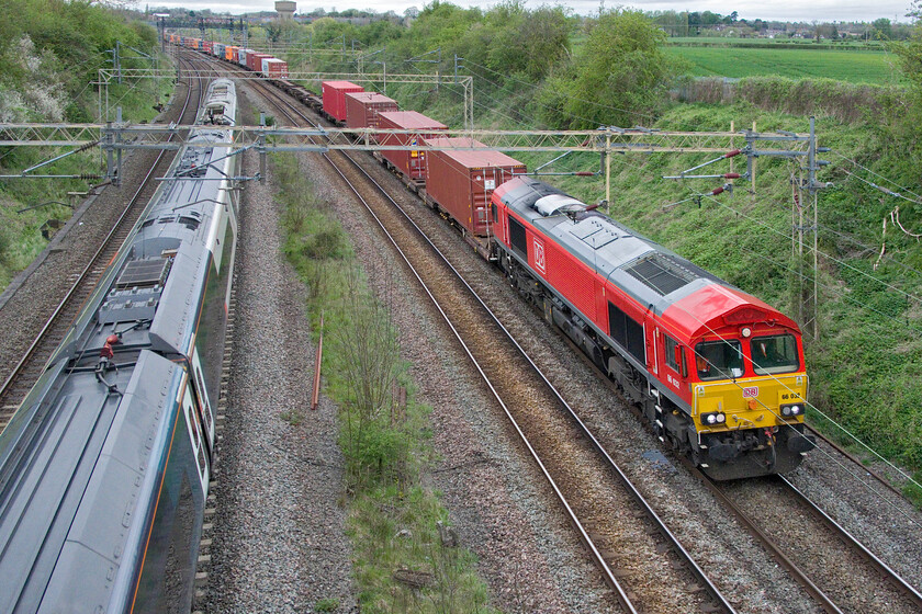 66032, 13.20 Trafford Park-London Gateway (4L56, 2E) & 390103, VT 17.17 Birmingham New Street-London Euston (1B54, 2L), Victoria bridge 
 A burst of DB Cargo red brightens up a dull April afternoon! 66032 leads the 4L56 Trafford Park to London Gateway service, again very well loaded, just south of the Northamptonshire village of Roade, seen in the background including my own house! Recently named (October 2023) 390103 'Asquith Xavier' also heads south, but slightly faster than the 4L56, working the 17.17 Birmingham New Street to Euston AWC service. 
 Keywords: 66032 13.20 Trafford Park-London Gateway 4L56 390103 17.17 Birmingham New Street-London Euston 1B54 Victoria bridge Asquith Xavier