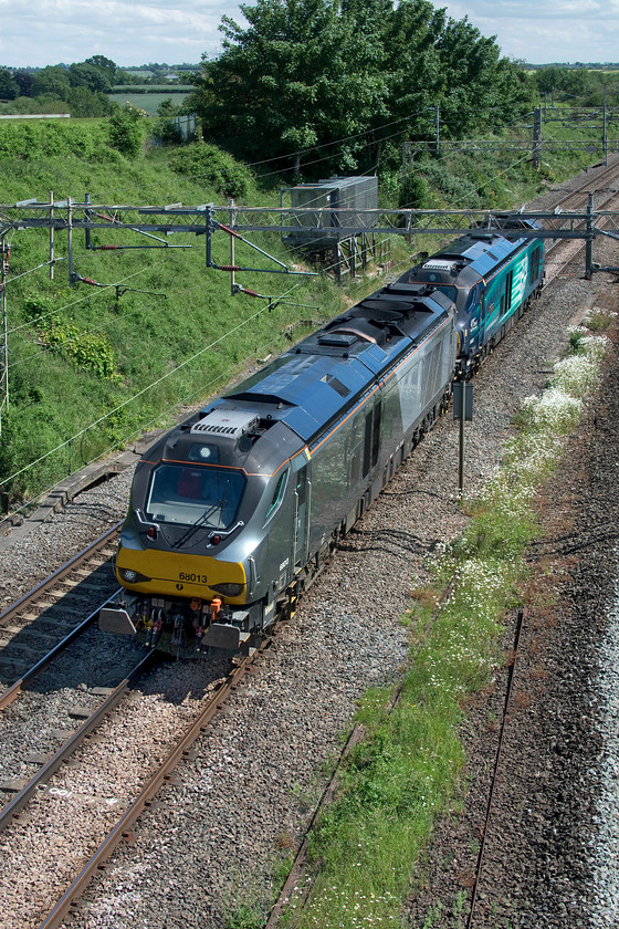 68013 & 68008, 09.35 Wembley LMD-Crewe Gresty Bridge (0K99, 53L), Victoria bridge 
 Passing through the Northamptonshire countryside on a hot summer's day 68013 and 68008 'Avenger' are seen about to go under Victoria bridge near Roade as the 0K99 09.35 Wembley to Crewe Gresty Bridge. The first of the two locomotives is in its Chiltern livery being operated by them but owned and maintained by DRS hence its move from North London to Crewe for an examination or maintenance of some kind. As the trailing Class 68 is one of two DRS liveried locos fitted with American Railroads (AAR) push-pull equipment allowing them to operate Mk.IIIs I suspect that this was heading north for the same reason as 68013. 
 Keywords: 68013 68008 09.35 Wembley LMD-Crewe Gresty Bridge 0K99 Victoria bridge Chiltern DRS Avenger