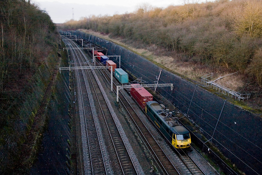 90016, 12.32 Crewe Basford Hall-Ipswich (4L96), Roade Cutting 
 In mid-winter, the depths of Roade cutting is a dark and tricky place to take photographs. Even though the sky is bright and that the sun is shining, Freightliner branded 90016 is poorly lit leading the 12.32 Basford Hall to Ipswich. Normally, this train would continue on the short distance from Ipswich to Felixstowe but on Saturdays, it only is timetabled as far as the Suffolk town. 
 Keywords: 90016 12.32 Crewe Basford Hall-Ipswich 4L96 Roade Cutting