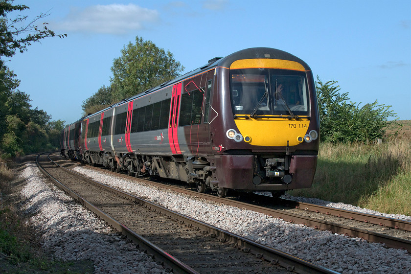 170114, XC 13.22 Birmingham New Street-Cambridge (1L42, 4L), Wymondham crossing 
 With a friendly wave from the driver of 170114, the 13.22 Birmingham New Street to Cambridge rushes past the remote and very quiet Wymondham crossing. When a train approaches, there are no wailing sirens or barriers crashing down as the gates stay firmly closed to road traffic unless a vehicle wants to cross the railway. The wooden gates are manually operated by a signalman (or signalwoman on the day of our visit) if the lines are clear. 
 Keywords: 170114 13.22 Birmingham New Street-Cambridge 1L42 Wymondham crossing CrossCountry Trains