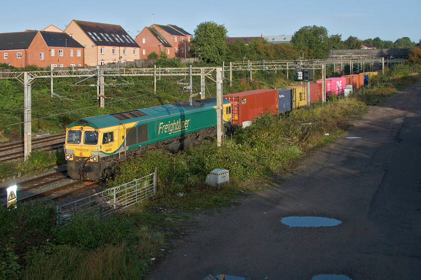 66420, 03.39 Garston-London Gateway (4L52, 3E), site of Roade station 
 I expect the the driver of 66420 would be blinking as his train emerges from the darkness of Roade cutting into the bright and low September morning sunshine. The Freightliner 66 is leading the 4L52 03.39 Garston to London Gateway service past the site of Roade's former station the entrance road to which can still be seen to the right of the photograph. 
 Keywords: 66420 03.39 Garston-London Gateway 4L52 site of Roade station Freightliner