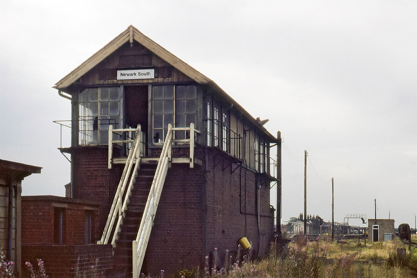 Newark South signal box (Closed) (GN, not known) 
 I dare not think about how I got this photograph! I suspect that Graham and I chanced our luck and entered the yard complex to the south of Newark station and walked as far as we dared to get this picture of the closed Newark South signal box. The ECML is to its left and the station just visible in the distance. On the extreme right is a class 08 shunter probably struggling to find work in the overgrown and rationalised yard. The box is an impressive Great Northern box of unknown date; can anybody advise. Notice that the door is open but appears bereft of any levers or internals. I do not recall if we climbed the steps and had a look round, I would hope not! 
 Keywords: Newark South signal box