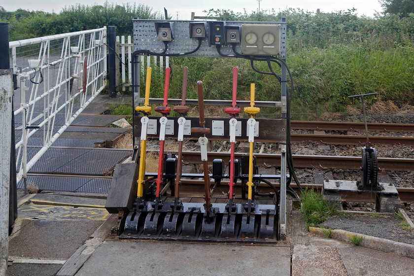 Limestone Hall MCG ground frame 
 A real oddity of the Cumbrian Coast route is the presence of two manually controlled gate crossings within less than a mile of each other. What is unusual about these crossings is that they both control semaphore arms but are not absolute block being within the section from Silecroft (to the north) and Millom (to the south). I presume that neither Silcroft or Millom can pull off their signals until the crossings have closed their gates and pulled their respective home signals off. Limestone Hall MCG ground frame is seen adjacent to the A5053 level crossing with no protection offered to the signalman. On a June day such as this there would be no problems but just imagine operating the levers on a cold and wild night in January! At least the signalman has a small hut in which he can take shelter in between trains located just to the right of me! 
 Keywords: Limestone Hall MCG ground frame