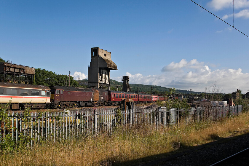 47500, general view, Carnforth WCR 
 A wide-angled view of the former Steamtown yard now owned and operated by West Coast Railways at Carnforth. The scene is dominated by the huge mechanical coaling stage and the smaller ash plant behind. Both of these concrete structures are listed by Historic England so their future is assured. In the foreground sandwiched between various stock is the fire-damaged 47500. Unlike the coaling stage and ash plant, which are Grade 2 listed, I suspect that the Class 47 has a bleak future and a meeting with the scrap man! 
 Keywords: 47500 Carnforth WCR West Coast Railways