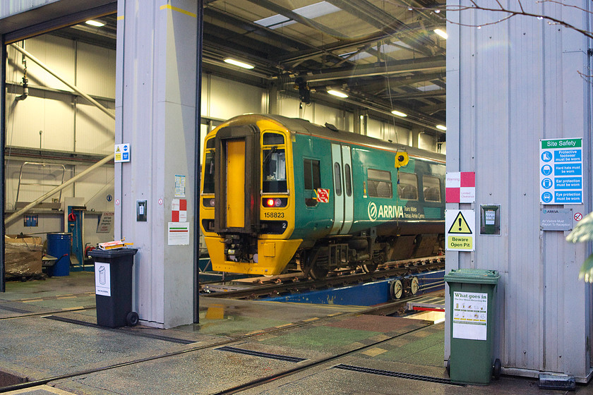 158823, stabled, Machynlleth Depot 
 158823 sits stabled in Machynlleth depot receiving attention. This is ATW's main maintenance depot for its 158 DMUs. The depot was opened in 2007 to great fanfare replacing the Victoria era shed that was not suitable for modern traction. The new depot has very high environmental credentials featuring rainwater harvesting and wind turbine power. Notice the wheelie bins in the foreground with the small laminated image above them reminding staff what to recycle and where. 
 Keywords: 158823 Machynlleth Depot