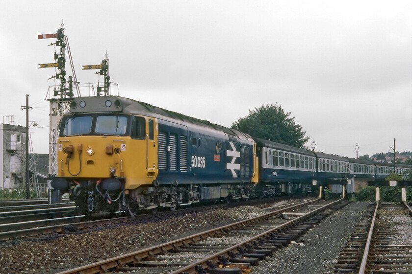 50035, 09.10 London Waterloo-Exeter St. David's (1V09), Salisbury East Yard 
 After a fairly long wait in Salisbury East Yard and after photographing more mundane trains (but some forty years later I am so glad that I did!) I was rewarded with my first London Waterloo train. The 1V09 09.10 Waterloo to Exeter St. David's approaches Salisbury through the East Yard with me positioning myself at the far eastern end led by 50035 'Ark Royal'. Either, I was overcome by the occasion or the locomotive or I was not ready for its arrival but the composition is very poor with my partly obliterating the fine up bracket signal and missing off the rear of the train! 
 Keywords: 50035 Ark Royal 09.10 London Waterloo-Exeter St. David's 1V09 Salisbury East Yard