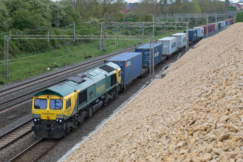 66418, 08.25 Crewe Basford Hall-Felixstowe North (4L93, 6E), Ashton Road bridge 
 The second up Freightliner within ten minutes gave me no time to get to another location so the same view as the last but one photograph will have to suffice. Int its revised Freightliner livery 66418 'Patriot-In Memory of Fallen Railway Employees' leads the 08.25 Crewe Basford Hall to Felixstowe North past Roade about to pass under Ashton Road bridge. It's interesting to note how the colour of the stone that was placed on the embankment following stabilisation work earlier in the year has begun to mellow. It started off almost white but is now yellowing as the weathering process takes place. 
 Keywords: 66418 08.25 Crewe Basford Hall-Felixstowe North 4L93 Ashton Road bridge Freightliner Patriot-In Memory of Fallen Railway Employees