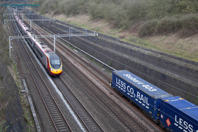 390043, VT 09.38 Glasgow Central-London Euston (1M05, 1E) & 13.09 Daventry-Purfleet (4L98), Roade Cutting 
 As the tail-end of the 13.09 Daventry to Purfleet 4L98 Freightliner passes through Roade Cutting, 390043 is about to overtake it working the 09.38 Glasgow Central to Euston. 
 Keywords: 390043 1M05 13.09 Daventry to Purfleet 4L98 Roade Cutting