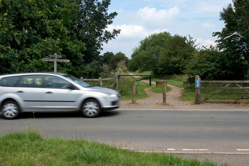 Former Spratton level crossing 
 A car crosses the former level crossing on the Spratton to Brixworth road in Northamptonshire. The line ran between Northampton and Market Harborough being finally closed to freight traffic in 1981. There was once a small station at this location that closed very early in 1949 situated just behind where I am standing that is now a car park for users of the Brampton Valley Way. There was also a signal box that protected the level crossing. 
 Keywords: Former Spratton level crossing