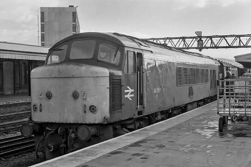 46011, unidentified down working, Gloucester station 
 I had travelled behind 46011 from Bristol Temple Meads to here, at Gloucester. It is the process of being detached from its unidentified down working whilst a replacement locomotive has moved off from Horton Road depot and will be being attached to what will be the front of the train when it gets away to head northwards towards Birmingham. I rejoined the train to travel the short distance to Cheltenham for my interview at the College of St. Pul and St. Mary. Notice the Royal Mail trolleys on the platform, a useful piece of railway infrastructure widely used by us spotters back dring this era! 
 Keywords: 46011 unidentified down working Gloucester station Peak