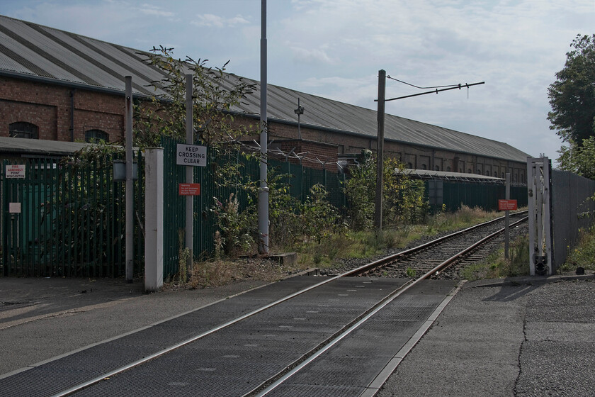 Access track, Wolverton works 
 With a building that was once part of the mighty Wolverton Works in the background now in use by a haulage company the single access line into the remains of the Works is seen. In this view, looking south towards the tunnel that goes under the up and down fast lines, a disused and rather sad looking loading gauge can be seen still standing. 
 Keywords: Access track Wolverton works