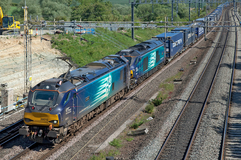 88010 & 68016, 06.18 Mossend-DIRFT (4Z27, 8E), Ashton Road bridge 
 Having seen 88010 'Aurora' and 68016 yesterday afternoon, see.... https://www.ontheupfast.com/p/21936chg/29048920804/x88010-68016-14-10-dirft-mossend they are seen again returning leading the 4Z27 06.18 Mossend to DIRFT. The train is seen about to pass under Ashton Road bridge just south of Roade passing the currently closed Amco Giffen (for Network Rail) worksite to secure the slipping embankment. These weekend Anglo Scottish heavily diverted workings are set to continue for a few more weeks as engineering work continues in the Borders necessitating the complete closure of the WCML between Lockerbie and Carstairs. 
 Keywords: 88010 68016 06.18 Mossend-DIRFT 4Z27 Ashton Road bridge Tesco Express Aurora