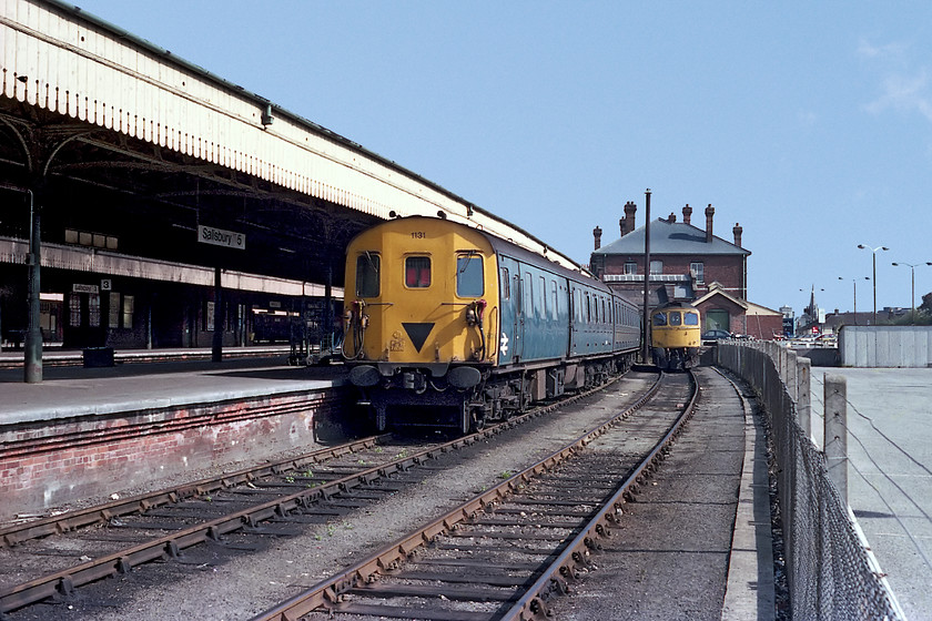 1131 & 33032, stabled, Salisbury station 
 Taken by leaning over the fence from the empty station car park, 33032 is seen stabled in the siding. Next to it on the bay platform 5 or Salisbury 5 as the running-in sign states, is a Southern Region DEMU 1131. I really liked these units and particularly the noise that they made from their English Electric 4SRKT Mk. II engines. This particular 1962 set became 205031 and then 930301 after conversion to a Sandite unit. 
 Keywords: 1131 33032 stabled Salisbury station