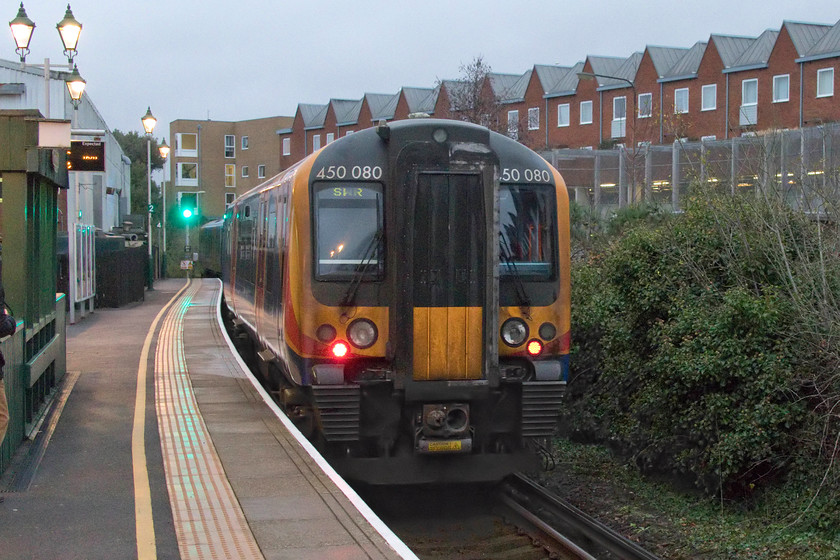 450080, SW 15.57 Lymington Pier-Brockenhurst (1J40, RT), Lymington Town station 
 I am glad that 450080 is just leaving Lymington Town station as the best shutter speed that I could get was 1/250th second and even then with an ISO of 8000! The unit was working the 15.57 Lymington Pier to Brockenhurst, a journey of some five miles and twenty-nine chains with just this intermediate stop. The question to be asked is why does this service carry the reporting number of 1J40? A class one is 'Express Passenger' service and this one is far from this! When I last visited Lymington Town station the land now covered by the flats was occupied by warehousing. However, that was fourteen years ago when my son was five and he is now at university. Where has the time gone? 
 Keywords: 450080 15.57 Lymington Pier-Brockenhurst 1J40 Lymington Town station South Western Railway SWR