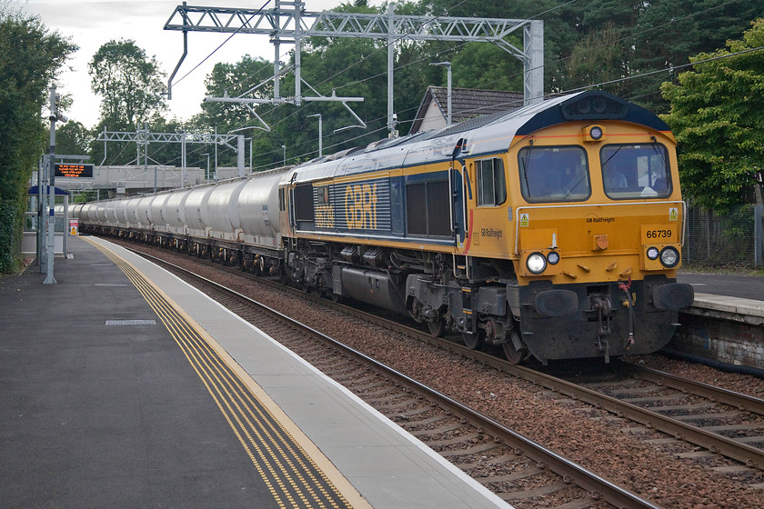 66739, 08.07 Fort William Alcan-North Blyth Alcan (6E45), Hartwood station 
 66739 'Bluebell Railway' leads the 08.07 Fort William to North Blyth Alcan train through Hartwood station. This train runs regularly from Alcan's smelter at Fort William to collect the main raw material used in the manufacturing of aluminum, alumina. This is imported into the UK at the North Blyth facility. The importing of alumina to and the export of finished aluminum from the huge Fort William factory is one of the factors that has kept the West Highland line open. 
 Keywords: 66739 08.07 Fort William Alcan-North Blyth Alcan 6E45 Hartwood station