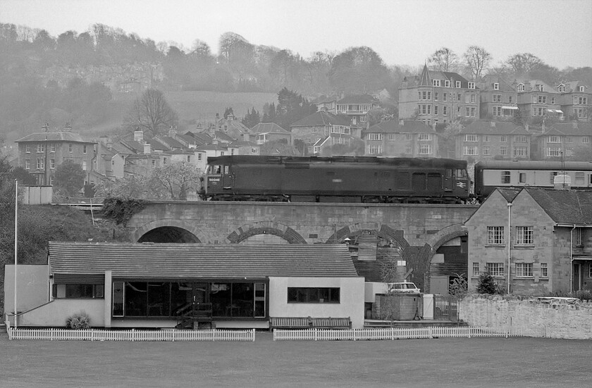 50048, unidentified up working, Bath cricket ground 
 Whilst the number is a little out of focus with a bit of work in Photoshop I believe that this Class 50 leaving Bath is 50048 'Dauntless' at least the number plate looks to be about the right size and there is no crest. The unidentified up service is passing Bath's cricket ground crossing Dolmeads viaduct. As I was standing on Bath's North Parade I must have been using a zoom lens but I am unsure as to which one I was using? 
 Keywords: 50046 up working Bath cricket ground Ajax