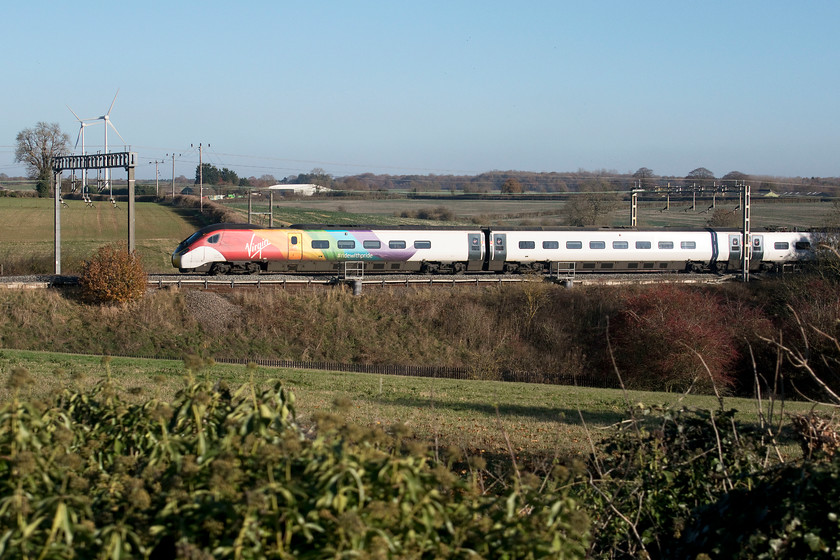 390045, VT 12.05 London Euston-Liverpool Lime Street (1F16, 6L), Roade Hill 
 Striking a bright look look as it passes the Northamptonshire countryside near to Roade, 390045 'Virgin Pride' works the 12.05 Euston to Liverpool Lime Street. This one-off branding certainly is different and looks smart. 
 Keywords: 390045 12.05 London Euston-Liverpool Lime Street 1F16 Roade Hill