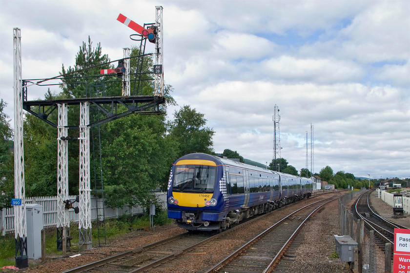 170452, SR 12.09 Glasgow Queen Street-Inverness (1H51), Aviemore station 
 The up starter, AV28, is pulled off to allow the departure of 170452 working the 12.09 Glasgow Queen Street to Inverness. The signal posts, both those in and out of use are of a typical Caledonian Railway latticed design but al are devoid of their finials. Notice the track to the right of the fence, this is the track of the Strathspey Railway leading to Broomhill. 
 Keywords: 170452 12.09 Glasgow Queen Street-Inverness 1H51 Aviemore station ScotRail