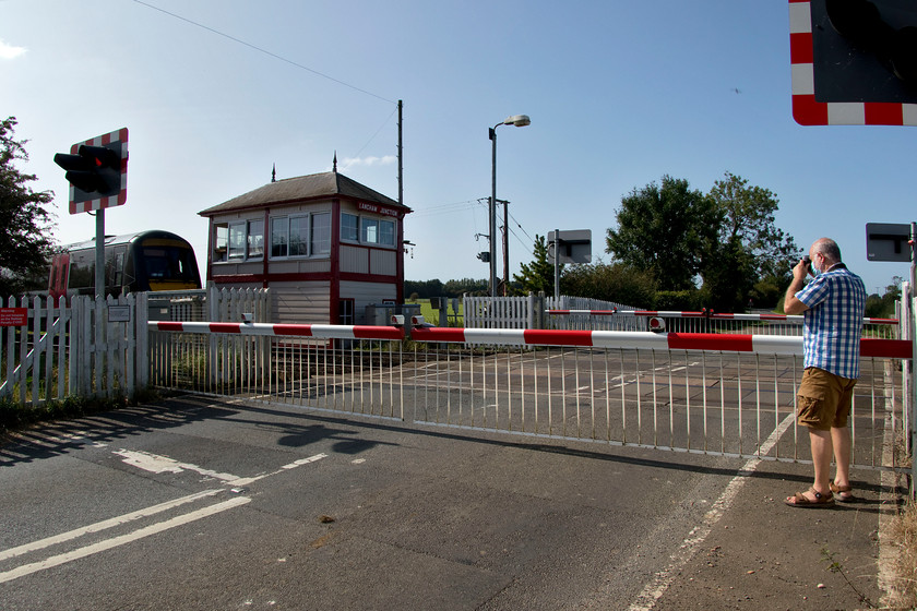 170115, XC 11.27 Stansted Airport-Birmingham New Street (1N53, 24L), Langham Junction level crossing 
 Andy attempts a 'grab shot' right into the sun of the delayed 11.27 Stansted Airport to Birmingham New Street CrossCountry service being worked by 170115. I have gone more for an interest image showing the super Midland box dating from 1890 and the crossing barriers. Notice the angle that this box is at. This is not to do with the lens or my photographic ineptitude but it really does appear to be sinking at the rear. An earlier image taken some years ago showed it to be also doing it then but that it has got no worse. Also notice that Andy is suitably attired wearing his face-covering! 
 Keywords: 170115 11.27 Stansted Airport-Birmingham New Street 1N53 Langham Junction level crossing Cross Country Trains Midland Railway