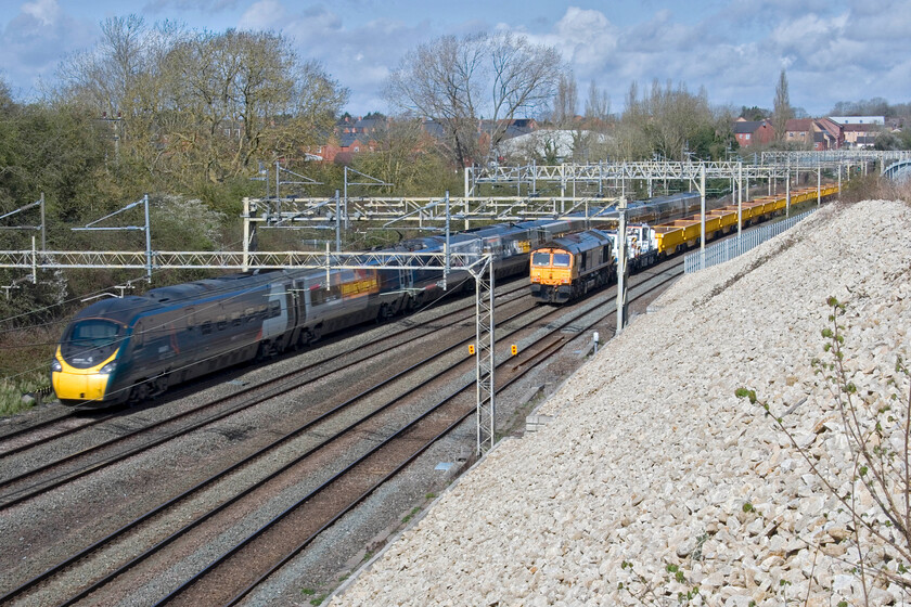 390050, VT 09.52 Milton Keynes Central-Birmingham New Street (9G55, 3L) & 66766, engineering train, Ashton Road bridge 
 Deliberately using a slow shutter speed (1:100/sec) to emphasise that 390050 working the 09.52 Milton Keynes to Birmingham New Steet is at line speed as it passes Roade but that the engineering train was stationary. 66766 'Gail Richardson' is at the rear of a short rake of JNA-Y box wagons a couple of Plasser & Theurer TJC60 self-propelled heavy-duty twin jib cranes (DRP 78215 and DRP 78219). The engineering train was only to make the short journey to its worksite at the nearby Sergo Logistics Park which would hopefully be fully rail-connected by the end of the Easter weekend; we'll see! 
 Keywords: 390050 09.52 Milton Keynes Central-Birmingham New Street 9G55 66766, engineering train Ashton Road bridge Avanti west coast Pendolino Gail Richardson GBRF