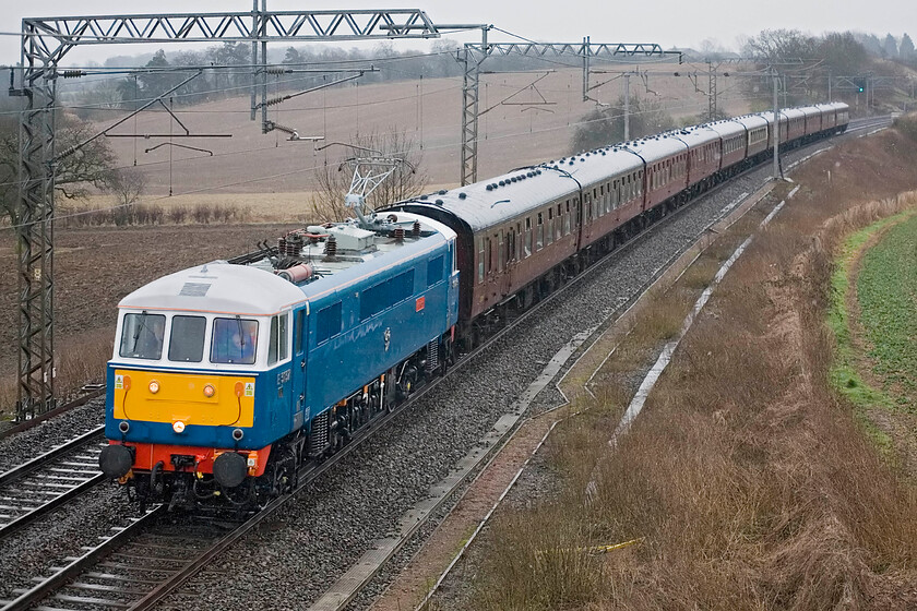 86259, outward leg of The Winter Cumbrian Mountain Express 2, 07.06 London Euston-Carlisle (1Z86), Milton Crossing 
 Preserved AL6 86259 'Les Ross/ Peter Pan' certainly brightens up a dismal grey morning at Milton Crossing between Roade and Blisworth. It is leading, appropriately, the 1Z86 Cumbrian Mountain Express that left Euston at 07.06 heading, ultimately, for Carlise with 60009 'Union of South Africa' taking over from the electric at Carnforth. 
 Keywords: 86259 The Winter Cumbrian Mountain Express 2 07.06 London Euston-Carlisle 1Z86 Milton Crossing AL^ AC Les Ross Peter Pan