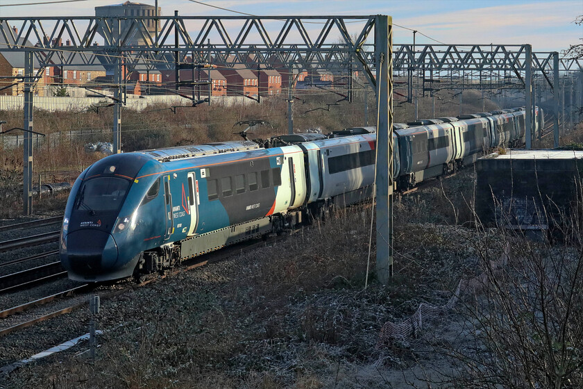 807001, VT 12.43 London Euston-Liverpool Lime Street (1F22, 3L), site of Roade station 
 Passing Roade 807001 is seen working the 12.43 Euston to Liverpool Lime Street Avanti service. It is still in the afternoon sunshine that is now low in the sky on this bitterly cold afternoon with the temperature still below freezing. Noice the large grey brutalist water tower in the background. This was recently featured on an episode of Kevin McCloud's Grand Designs, see... https://www.northamptonchron.co.uk/arts-and-culture/film-and-tv/northamptonshire-familys-ambitious-village-water-tower-conversion-features-on-channel-4s-grand-designs-4839191 
 Keywords: 807001 12.43 London Euston-Liverpool Lime Street 1F22 site of Roade station Avanti West Coast Evero