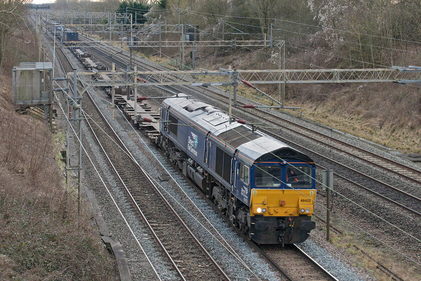 66423, 08.02 Tilbury-DIRFT (4M07, 4E), Victoria bridge 
 On my way back from Milton Keynes with a few minutes in hand and freight due I stopped off at my favourite local spot Victoria Bridge between Roade and Ashton. After a short wait, regular performer 66423 appeared leading the 4M07 08.02 Tilbury to Daventry service. This is usually a well-loaded train but in common with a fair few that I have observed recently it was noticeably short and with very few boxes, I estimated there to be half a dozen and all towards the rear. This begs a worrying question as to what exactly is going on with trade and shipping in these very uncertain times? 
 Keywords: 66423 08.02 Tilbury-DIRFT 4M07 Victoria bridge DRS Direct Rail Services