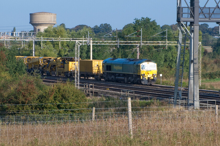 66530, switched off, HOBC train, Roade Hill 
 Unfortunately, taken the wrong side of the sun 66530 is seen at the head (or is it the tail?) of an HOBC (High Output Ballast Cleaning) waiting on the up slow line just south of Rode in Northamptonshire. Living just the other side of the line at this location it was strange seeing a train stationary on the line with its engines off. 
 Keywords: 66530 HOBC train Roade Hill Freightliner