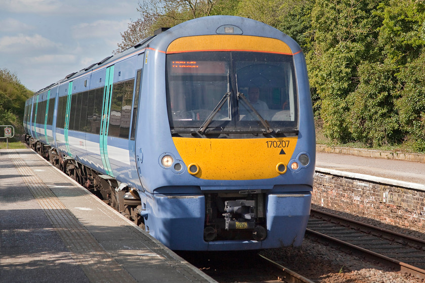 170207, GE 10.44 Cambridge-Ipswich (2W13, 1E), Dullingham station 
 In the rather drab blue livery of Greater Anglia, 170207 passes through Dullingham station having just set out out working the 10.44 Cambridge to Ipswich service. It is not running wrong-line and I have not flipped the image but it's merely travelling on the bi-directional through road at Dullingham. The line to the right is a rarely used intermediate passing loop and was fairly rusty indicating that no trains had passed over it for sometime. 
 Keywords: 170207 2W13 Dullingham station