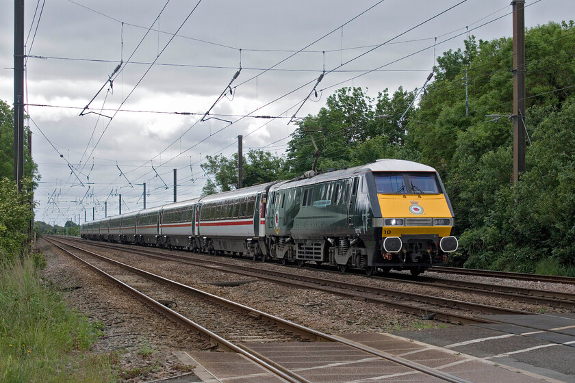 91110, GR 10.33 London King's Cross-Leeds (1D10, 12L), Lolham level crossing 
 91110 'Battle of Britain Memorial Flight' roars past Lolham level crossing a short distance north of Helpston Junction working the 1D10 10.33 King's Cross to Leeds service. The use of the IC225 sets on the ECML was thought to be coming to an end but it looks like it will continue for some time yet with some other locomotive and sets, presently stored, perhaps being prepared to re-enter service again as passenger numbers grow again post COVID. If I were making a journey between London and Leeds I would certainly choose to travel on one of the IC225 rostored services enjoying the sumptuous travelling experience of a Mk. IV over an Azuma. 
 Keywords: 91110 10.33 London King's Cross-Leeds 1D10 Lolham level crossing Battle of Britain Memorial Flight