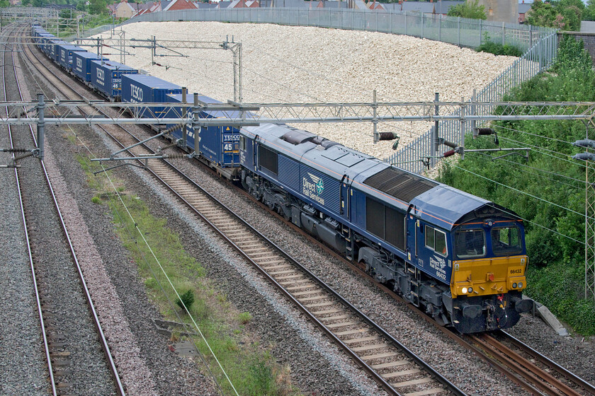 66432, 13.09 DIRFT-Tilbury (4L48, RT), Ashton Road bridge 
 The Sunday only 4L48 'Tesco Express' is seen passing to the south of Roade about to go under Ashton Road bridge. The 13.09 Daventry to Tilbury train is being led by DRS regular performer 66432. This is a photograph taken completely 'blind' by raising the camera up and over the bridge parapet with a 'hope for the best' approach; in this particular case it almost worked but for the rear of the locomotive not quite clearing the stanchion. 
 Keywords: 66432 13.09 DIRFT-Tilbury 4L48 Ashton Road bridge DRS Tesco Express