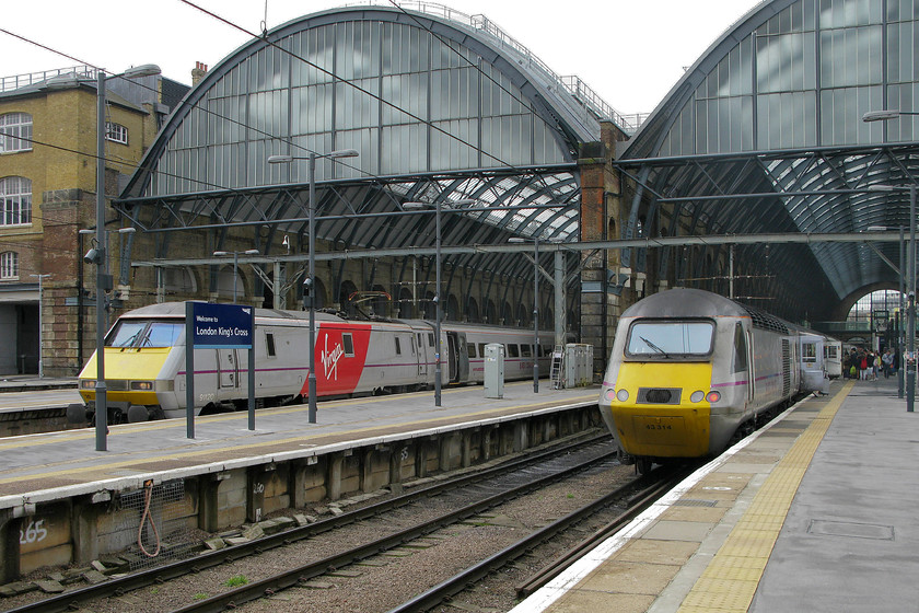 91120, GR 12.30 London King`s Cross-Newcastle (1N17) & 43314, GR 12.35 London King`s Cross-Leeds (1D14), London King`s Cross station 
 Trains in transition at King's Cross. Still wearing their grey state-owned East Coast livery, that itself was based around the previously failed operator National Express' paint scheme, 91120 and 43314 wait at King's Cross. From the first day of last month, Stagecoach (90%) and Virgin (10%) have taken over the franchise in a joint venture branded as Virgin East Coast. The branding has been applied to the side of 91120 as it waits with the 12.30 to Newcastle. The HST retains its East Coast branding as the leading power car of the 12.35 to Leeds. 
 Keywords: 91120 12.30 London King`s Cross-Newcastle 1N17 43314 12.35 London King`s Cross-Leeds 1D14 London King`s Cross station