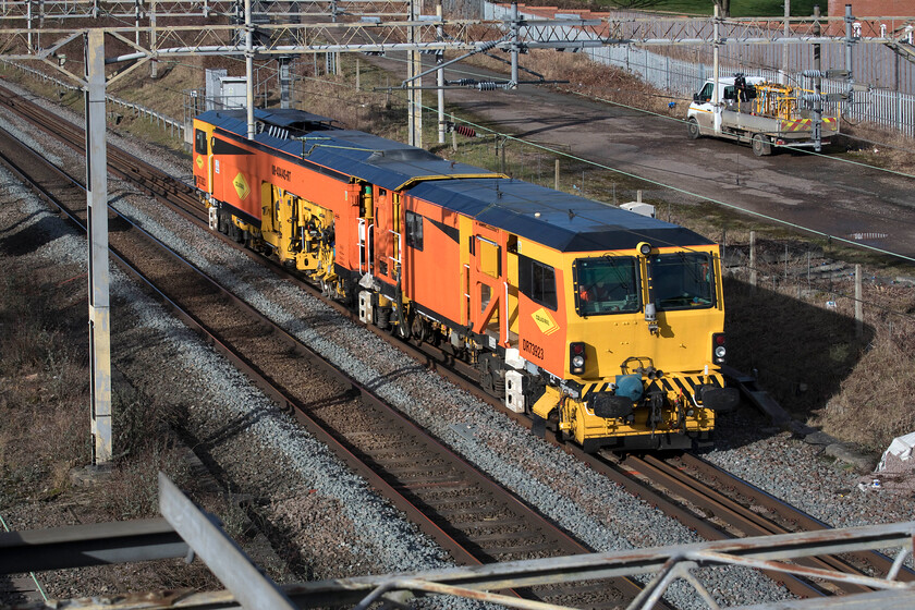 DR73923, 10.50 Nuneaton A Sidings-Bletchley CE Sidings (31L), site of Roade station 
 To see a Colas tamping machine always brightens up a photograph with its very distinctive livery whatever the weather! Regular performer DR73923 heads south along the WCML as the 10.50 Nuneaton to Bletchley move probably in association with some forthcoming weekend engineering work. The Tamper is seen passing the site of Roade station from the village's Gravel bridge as it is known locally. 
 Keywords: DR73923 10.50 Nuneaton A Sidings-Bletchley CE Sidings site of Roade station Colas Rail Tamping machine