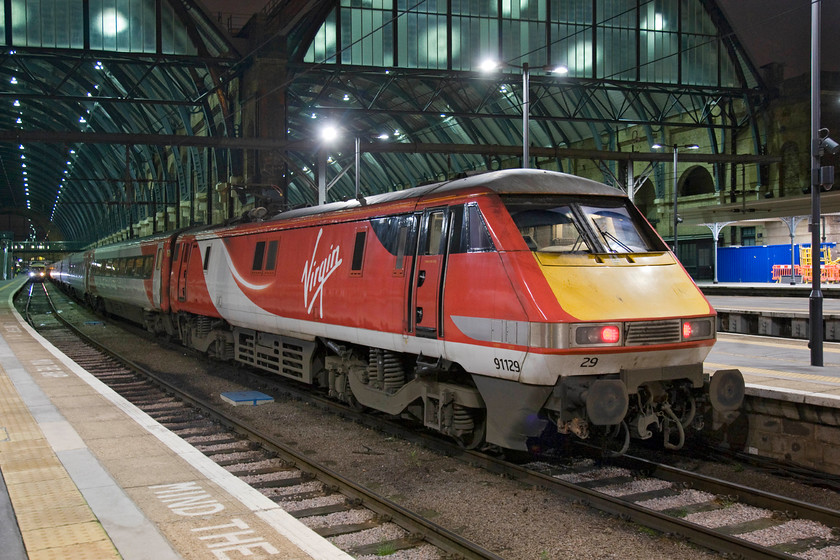 91129, GR 20.49 London King's Cross-Bounds Green TMD ECS (5Y46), London King's Cross station 
 The recently installed LED lighting at King's Cross provides lighting of a brilliant nature being neutral to the nighttime photographer who may be mad enough to be out on the platform end on a winter's Saturday night! 91129 sits idle at the country end of the station waiting to return to its Bounds Green depot at 20.49. There it will be serviced and cleaned ready for its next day in service on the ECML. 
 Keywords: 91129 20.49 London King's Cross-Bounds Green TMD ECS 5Y46 London King's Cross station VTEC Virgin East Coast