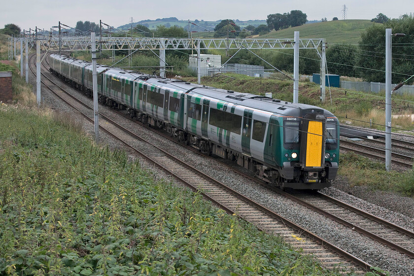 350116 & 350258, LN 11.46 London Euston-Crewe (1U33, 2L), Den bridge SJ742477 
 The view south from Den bridge as seen here is an interesting one despite a seemingly ordinary vista. To the left of the electrification masts on the left-hand side of the photograph lies the county of Staffordshire whilst the running lines and everything to the right is all in Cheshire. Indeed, the county boundary follows this side of the line for a couple of miles southwards before diverging off to the west then following Checkley Brook. 350116 and 350258 pass this spot working the 11.46 Euston to Crew service that will arrive at its destination in five minutes time. 
 Keywords: 350116 350258 11.46 London Euston-Crewe 1U33 Den bridge SJ742477 London Northwestern Desiro