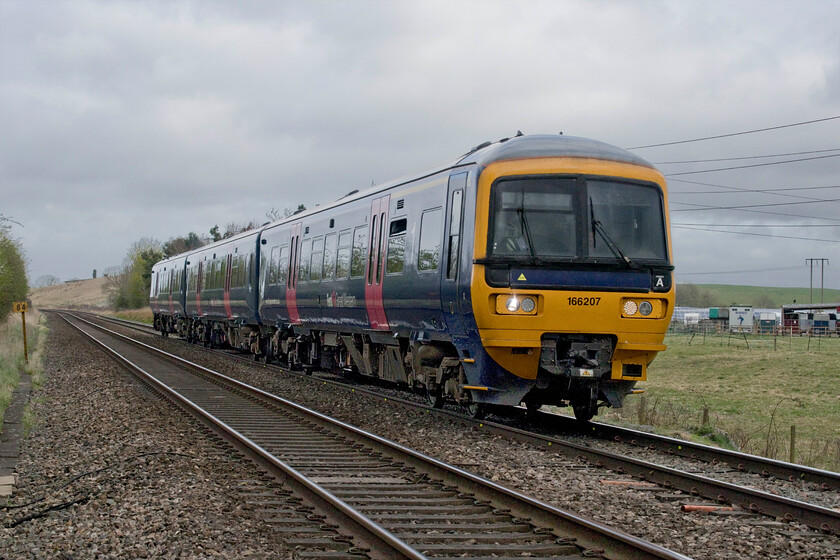 166207, GW 08.45 Great Malvern-Westbury (2C12, 2L), Brockhampton SO938262 
 166207 passes Brockhampton north of Cheltenham working the 08.45 Great Malvern to Westbury service. Notice the milepost to the left marking eighty-four miles. As this was the former Midland route this is the distance from the centre of their operation at Derby via Birmingham New Street. 
 Keywords: 166207 08.45 Great Malvern-Westbury 2C12 Brockhampton SO938262 GWR Great Western Railway