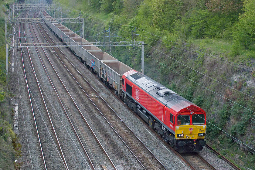 66079, 11.59 Burton-ot-Wetmore Yard-Acton TC (6V06,6E), Hyde Road bridge 
 Looking smart in its recently applied DB Cargo livery 66079 'James Nightall G.C. ' leads the 6V06 11.59 Burton-ot-Wetmore to Acton Yard empties through Roade cutting. The train is composed of a rake of ex EWS MBA box wagons often referred to as 'monster boxes'. This Class 66 is one of two, the other being 66079 'Benjamin Gimbert G.C.', which carry their nameplates on their cab ends rather than in the more normal location on the flanks. 
 Keywords: 66079 11.59 Burton-ot-Wetmore Yard-Acton TC 6V06 Hyde Road bridge DB Cargo James Nightall G.C.