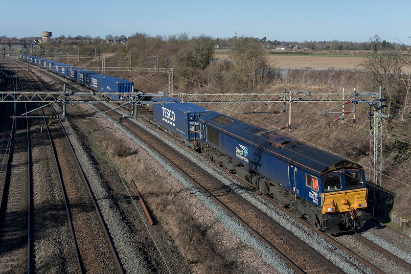 66432, 13.09 DIRFT-Tilbury (4L48, 70L), Victoria bridge 
 After some days of being electric hauled the 4L48 Tesco Express has reverted back again to diesel on this particular Sunday. With another relatively light loading 66432 makes easy work of the 13.09 Daventry (DIRFT) to Tilbury as it passes Victoria bridge near to Roade the houses if which can be seen in the background including my own! 
 Keywords: 66432 13.09 DIRFT-Tilbury 4L48 Victoria bridge Tesco Express