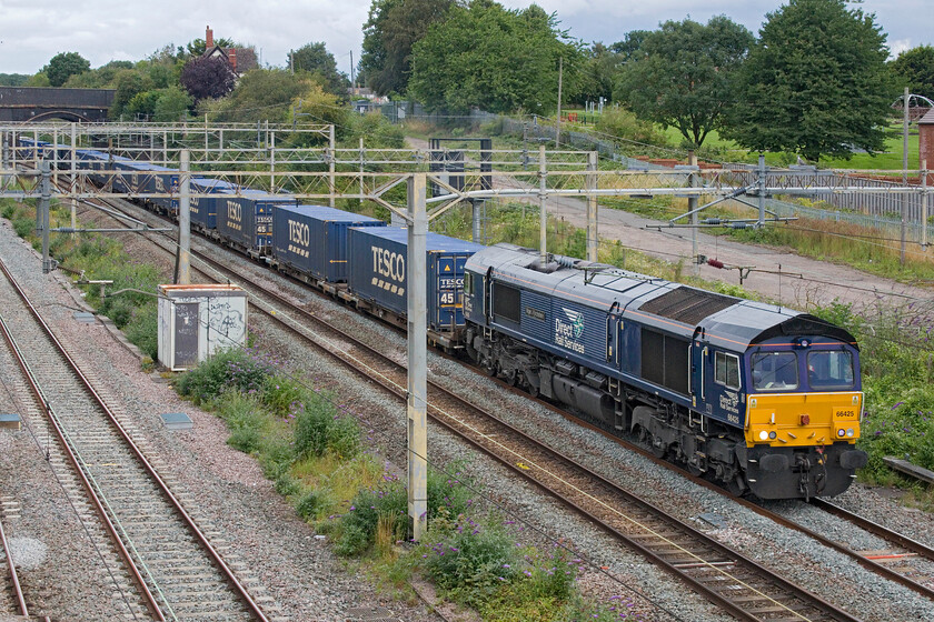 66425, 12.41 DIRFT-Tilbury Container Terminal (4L48, 9L), site of Roade station 
 The 4L48 'Tesco Express' 12.41 Daventry (DIRFT) to Tilbury passes Roade with 66425 'Nigel J Kirchstein 1957-2021' leading. This normally as regular as clockwork DRS operated service has been a little unreliable of late with some trains being rather lightly loaded but today it was back to normal! 
 Keywords: 66425 12.41 DIRFT-Tilbury Container Terminal 4L48 site of Roade station DRS Nigel J Kirchstein 1957-2021