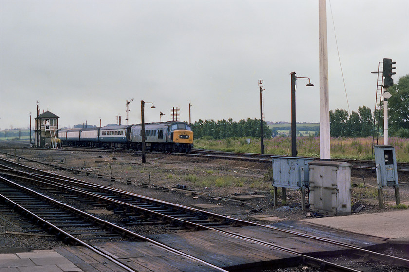 45121, unidentified down working, Kettering station 
 45121 takes the down fast line through Kettering station with an unidentified service from St. Pancras. The train is passing Kettering Station signal box and its associated signalling. This essentially rural scene is completely transformed now. The southern expansion of the town dominates the background and has covered the fields. Whilst there are still a pair of up and down lines, the rest of the railway infrastructure is much simplified. 
 Keywords: 45121 unidentified down working Kettering station