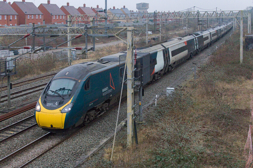 390104, 14.30 London Euston-Preston (1S76, 24E), site of Roade station 
 What seems like a routine photograph of a Penedolino passing Roade is not all that it seems to be. 390104 'Alstom Pendolino' works the 14.30 Euston to Preston at not much more than a walking pace following hot on the heels of the previous slow-moving diverted freight. Right behind this Pendolino were a number of other down services all running on caution signal to signal much to the frustration of the drivers and their passengers. 390104 never made up its lost time between here and Rugby arriving at Preston twenty-eight minutes late. 
 Keywords: 390104 14.30 London Euston-Preston 1S76 site of Roade station Avanti Pendolino Alstom Pendolino