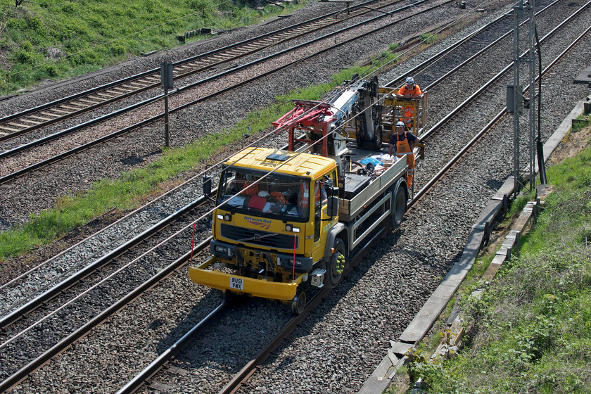 BU51VWX, down fast line, Victoria bridge 
 A Volvo FL6 road-rail vehicle, VRN BU51VWX makes its way along the down fast line at Victoria bridge between Roade and Ashton. As well as having the hydraulic platform at the rear it has a dummy pantograph just behind the cab. It is used for testing and checking the alignment of the wiring and was being put to use on the Weedon line due to an unprecedented week-long closure and possession enabled by the COVID-19 pandemic timetable. During these strange times, it is good to see that the three-man crew are socially distancing appropriately. 
 Keywords: BU51VWX down fast line, Victoria bridge