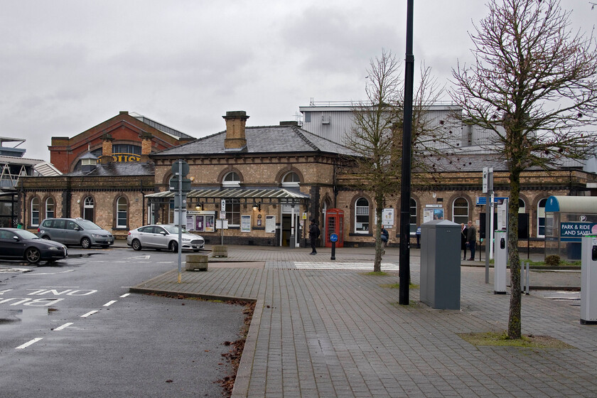 Frontage, Loughborough station 
 Ignoring the modern car parking and infrastructure in this photograph the frontage of Loughborough station is essentially the same as when I last photographed it back in 1981, see.... https://www.ontheupfast.com/p/21936chg/30036330549/frontage-loughborough-station Notice that the Brush factory behind the station is also virtually unchanged even though its role as a railway manufacturing facility has changed. 
 Keywords: Frontage, Loughborough station