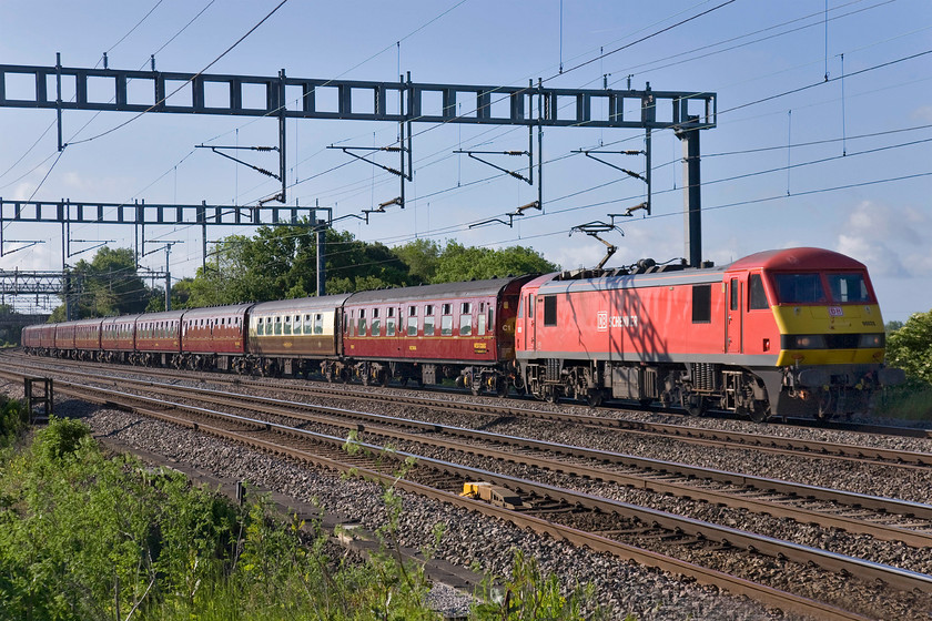 90029, outward leg of the The Cumbrian Mountain Express, 07.10 London Euston-Carnforth (1Z86), Ashton Road bridge 
 I think that the new DB all over red livery and grey sole bar suits the Class 90s very well especially when seen in superb summer sun such as this just south of Roade. 90029 leads the Railway Touring Company's Cumbrian Moutain Express charter from Euston to Carnforth where Royal Scot 46115 took over for the run over Shap to Carlisle and then south over the S & C. On the return run 90029 was failed at Crewe following a broken windscreen caused by flying ballast with 90035 taking over for the run back to Euston. 
 Keywords: 90029 outward leg of The Cumbrian Mountain Express 07.10 London Euston-Carnforth 1Z86 Ashton Road bridge Railway Touring Company