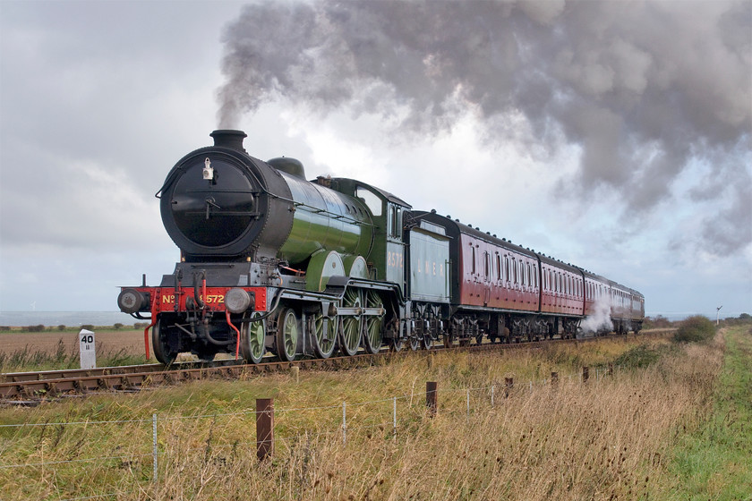 8572, 10.00 Sheringham-Holt, Weybourne TG123424 
 Former LNER 4-6-0 8572 gets into its stride on the approach to Weybourne station working the 10.00 Sheringham to Holt service. With the North Sea in the background, the North Norfolk Railway is moving away from the coast at this point commencing the climb up to Holt after leaving Weybourne. Notice the recently repainted milepost showing forty and a half miles from South Lynn Junction (King's Lynn).

There is an audio recording of this event at my Youtube site, see.... https://youtu.be/YGmLITLLz0c 
 Keywords: 8572 10.00 Sheringham-Holt Weybourne TG123424 B12 4-6-0 LNER