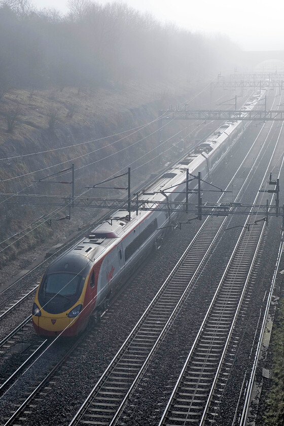 Class 390, VT unidentified down working, Roade cutting 
 Despite all the tech available to me I have been unable to identify this Virgin West Coast service passing through a misty Roade cutting. Not only do I not know where the train is heading but I don't know its number either! Never mind, just enjoy the strongly back-image and that it is on the down slow line due to engineering works and is thus travelling via Northampton. 
 Keywords: Class 390 unidentified down working Roade cutting Virgin Pendolino