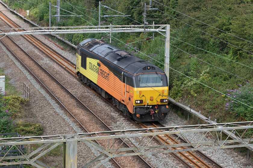 67027, 11.02 Derby-Hither Green (0Z27, 21E), A508 bridge 
 Just missing a patch of sunshine 67027 'Charlotte' passes through the southern end of Roade cutting about to go under the A508 bridge. It is working the 0Z27 11.02 Derby to Hither Green via two visits to Waterloo with a reversal at Kensington Olympia. This unusual and convoluted routing makes me wonder if this was some kind of route learning operation? 
 Keywords: 67027 11.02 Derby-Hither Green 0Z27 A508 bridge Colas Rail Charlotte