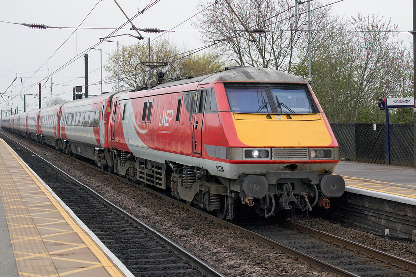 91124, GR 14.30 London King`s Cross-Newcastle (1N21, 5L), Northallerton station 
 91124 slows for its stop at Northallerton station leading the 14.30 King's Cross to Newcastle. Notice the damage to the front panel of the class 91, I suspect that relatively cosmetic issues such of this will not be attended to as these locomotives are going to be withdrawn form service starting in the next few weeks. What a different day to yesterday with its clear blue skies and spring sunshine! 
 Keywords: 91124 14.30 London King`s Cross-Newcastle 1N21 Northallerton station